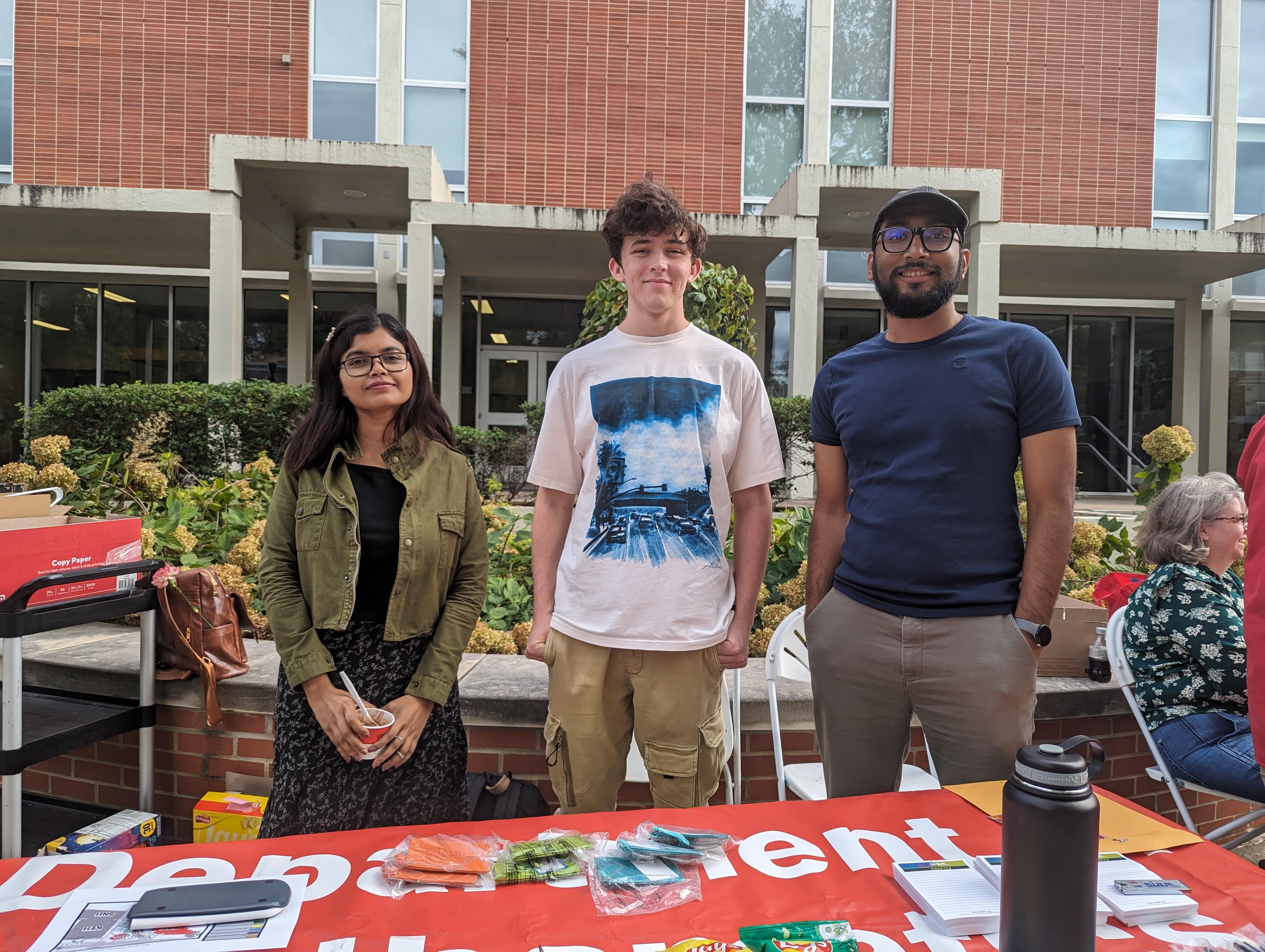 Three members of the WKU SIAM student chapter standing behind a table.